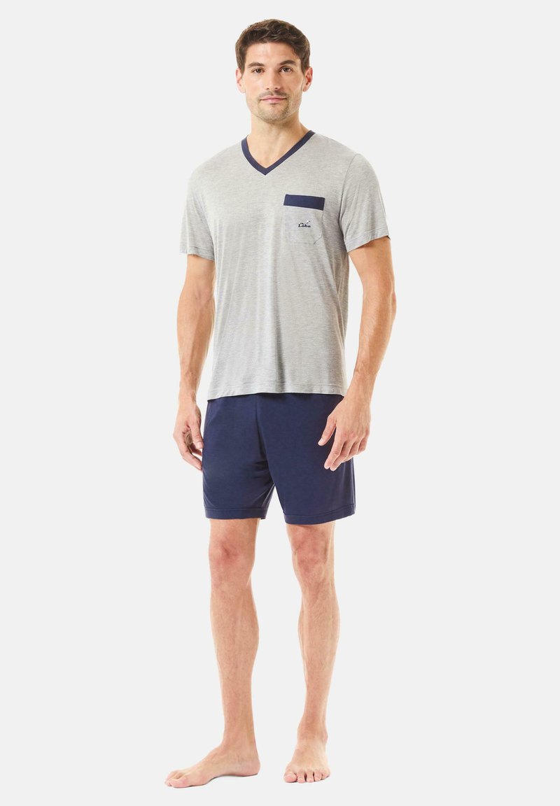 Camiseta de cuello en V de manga corta gris con bolsillo azul marino; combinada con pantalones cortos azul marino. Tejido suave, corte relajado, diseño minimalista.