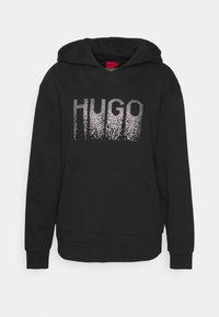 Czarna bluza z kapturem i kieszenią kangurzą, z napisem "HUGO" w gradientzie małych srebrnych kropek na wysokości klatki piersiowej oraz z kapturem na sznurku.