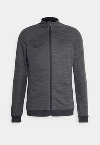 Nike zipová bunda v tmavě šedé barvě. Texturovaná látka s vodorovnými pruhy, přiléhavý střih, vysoký límec a logo na levé hrudi.