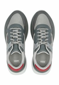Graue lässige Sneakers aus Mesh und Wildleder mit einer weißen Sohle, grauen Schnürsenkeln und einem roten Akzent an der Ferse.