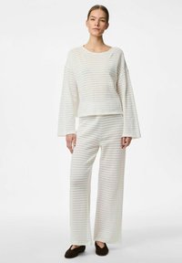 Set da lounge bianco in maglia a coste con maniche lunghe, scollatura ampia e pantaloni dalla vestibilità rilassata con sottili righe. Scarpa marrone slip-on.