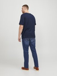 Mørkeblå bomull t-skjorte med korte ermer, rund hals, sammen med blå denim jeans og brune sko. Enkel design, uformell passform.