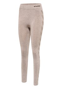 Beige aansluitende leggings met een subtiel chevronpatroon aan de zijkanten en een klein Hummel-logo dichtbij de tailleband op een witte achtergrond.