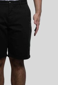 Shorts neri in cotone con orlo arrotolato, caratterizzati da chiusura con bottone frontale e tasche laterali, superficie liscia e vestibilità standard.