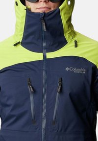 Giacca Columbia Titanium blu e verde lime con colletto alto, zip frontale, due tasche con zip e un tessuto liscio, resistente alle intemperie.