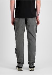 Pantalones cargo grises con múltiples bolsillos, hechos de una tela suave y duradera. Presentan un corte relajado y puños elásticos en los tobillos.