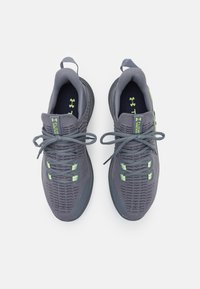 Ušlechtilé šedé sportovní boty s prodyšným síťovinovým svrškem, zelenými akcenty, plochými tkaničkami a odpruženou podrážkou. Obsahují smyčku pro snadné obouvání.
