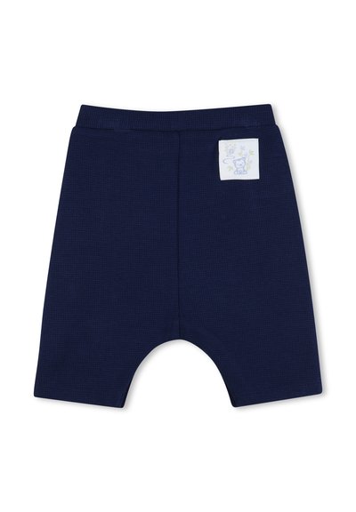 Shorts pour tout-petits bleu marine en tissu texturé avec un petit patch blanc représentant un tigre en dessin animé sur le devant supérieur.