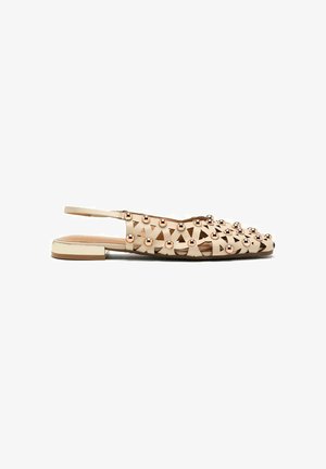 Scarpe flat beige slingback con motivi triangolari intagliati e accenti a cupola metallici. Presentano un tacco basso e una texture liscia.