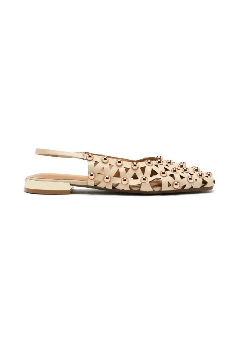 Beżowe płaskie buty typu slingback z wyciętymi trójkątnymi wzorami i metalicznymi akcentami w kształcie kopuły. Posiadają niski obcas i gładką teksturę.