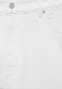 Gros plan d'un jean en denim blanc montrant la poche avant, la boucle de ceinture, le bouton métallique et les détails des rivets sur la texture du tissu.