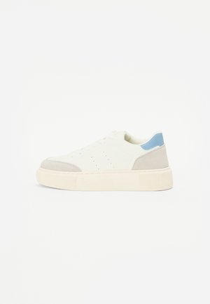 Witte sneaker met een gevulkaniseerde beige neus en hiel, lichtblauw accent op de achterkant en een dikke, gestreepte crèmekleurige zool.