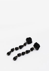Pendientes de gota de terciopelo negro con acentos florales y formas redondeadas, con herrajes dorados que conectan componentes texturizados.