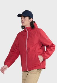 Rode lichte jacket met capuchon, voorzien van een voorzichtige rits, elastische manchetten en zijzakken. Gladde textuur en minimalistisch ontwerp.