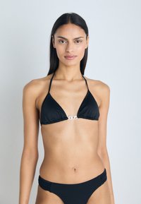Juodas bikini rinkinys, pasižymintis trikampio formos viršutine dalimi su sidabriniu akcentu centre, papildytu žemai sėdinčia apatine dalimi su surinktu dizainu.