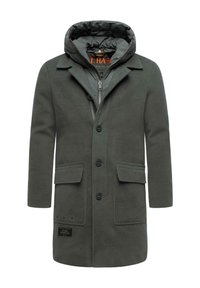 Cappotto esterno verde scuro con cappuccio, caratterizzato da una zip anteriore, quattro bottoni e due tasche a patta. Isolamento visibile nella fodera del cappuccio.
