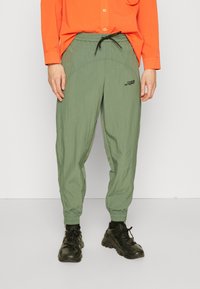 Zielone lekkie spodnie dresowe z elastycznym pasem, regulowanym sznurkiem i subtelnym logo na lewej udzie.