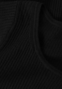 Tissu noir côtelé montrant un gros plan d'un décolleté avec une texture lisse et une forme arrondie. Les fibres sont tissées serré pour une durabilité optimale.