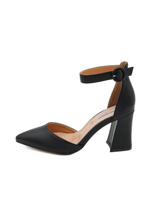 Scarpa nera con tacco alto, punta affusolata, cinturino alla caviglia e tacco largo. Realizzata in materiale liscio con un rivestimento interno beige.