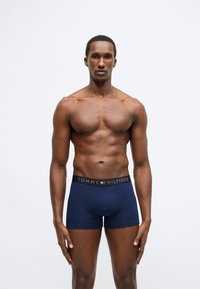 Meresinine boksershorts, millel on ruuduline muster ja must vöökoht kuldse "TOMMY HILFIGER" logoga. Sile ja veniv kangas.