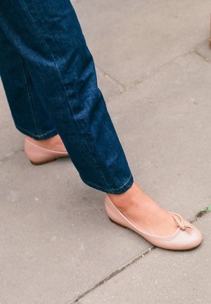 Bailarinas de cuero rosa claro con punta redondeada, detalle de lazo pequeño y tacón bajo, combinadas con pantalones de mezclilla azul oscuro.