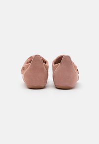Rosa mockaskor i slip-on-modell med rund bakdel, texturerad yta och subtila sömmar. Sulan är beige och något upphöjd.