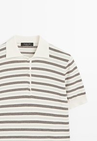 Bílá polokošile s krátkými rukávy s hnědými a černými vodorovnými pruhy a třemi knoflíky na légu, límec plochý s žebrovanou strukturou.