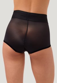 Persoon die hoge, semi-transparante zwarte shorts draagt met een effen zwarte tailleband, van achteren gezien tegen een neutrale achtergrond.