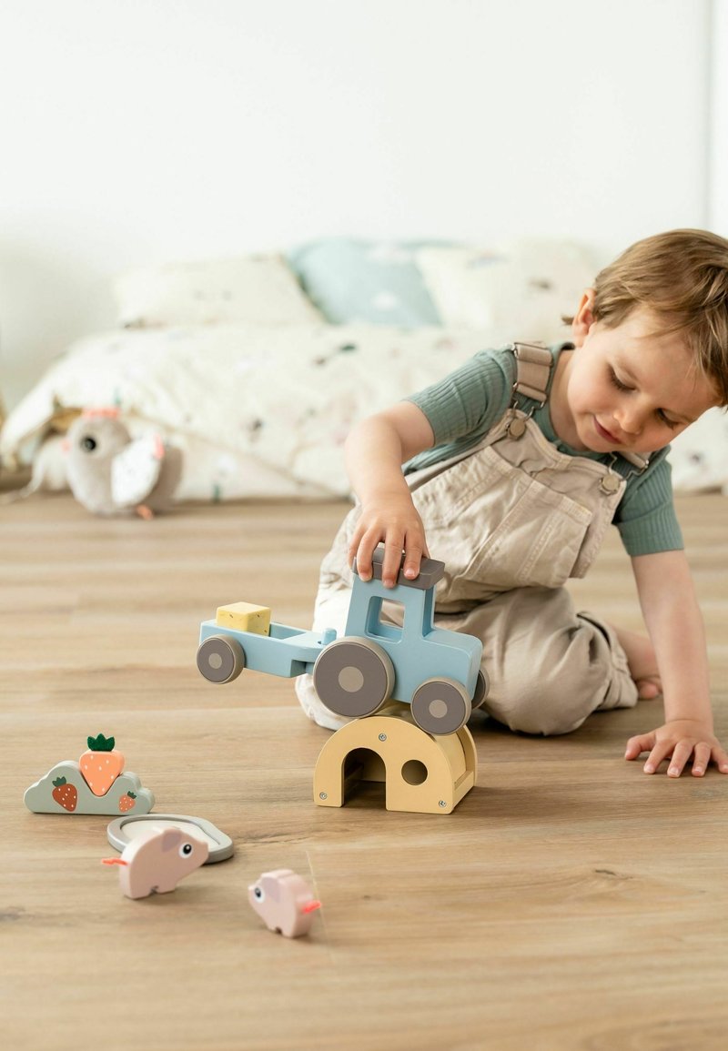 Heled puitkuiroja helesinise kerega ja hallide ratastega, virnastatud kollase kaare peale, �ümbritsetud väikeste loomafiguuride ja pilvekujuga plokiga.