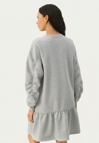 Grau Sweatshirtkleid mit langen Ärmeln, gerippten Manschetten und einem gerafften Rüschensaum. Aus weichem, strukturiertem Stoff gefertigt. Runder Ausschnitt.