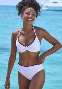 White bikini set featuring a triangular top with red and blue trim, and high-waisted bottoms with matching accent. Smooth, stretchy material.