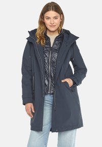 Marineblauer wasserdichter Parka mit abnehmbarem gestepptem Innenfutter, verstellbarer Kapuze, tailliertem Schnitt und Reißverschlusstaschen. Weicher Stoff.