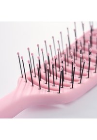 Rosa luftet hårbørste med fleksible svarte børstehår som er avrundet med rosa topper, på hvit bakgrunn.