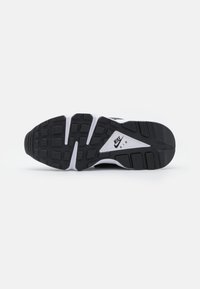 Sole of a black and white Nike Air sneaker with textured tread and logo in the center on a white background.