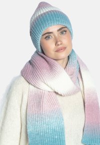 Zestaw czapka i szalik na drutach w pastelowych, gradientowych kolorach, z prążkowaną fakturą i szpiczastym zakończeniem czapki. Szalik ma efekt ombre przechodzący z różowego do niebieskiego.