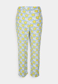 As calças estampadas têm um fundo azul com grandes flores amarelas e folhas verdes. O design é impresso numa tecido leve.