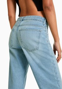 Light blue denim jeans with a high waist, straight legs, and two back pockets. The fabric shows a subtle texture and slight distressing.