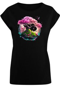 Schwarzes T-Shirt mit einem bunten Grafikdesign eines rosa Baumes und Blumen in einem kreisförmigen Muster, vor einer grünen Landschaft.