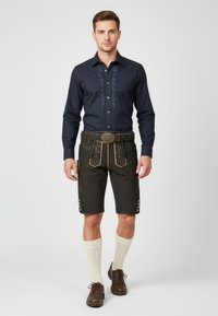 Dark blue button-up shirt with floral embroidery, black leather shorts with side buttons, brown shoes, and light socks.