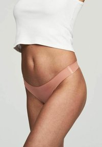 Perizoma seamless di colore rosa chiaro con design a vita bassa e lati sottili, realizzato in un materiale elastico e liscio.
