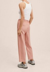 Lichtroze op maat gemaakte broeken met een elastische tailleband, zijzakken en een rechte pijp ontwerp, gecombineerd met grijze sportschoenen.