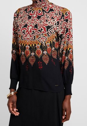 Long-sleeve blouse with intricate red, black, white, and gold paisley and floral patterns, high neckline, and smocked cuffs.