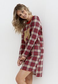 Czerwona i beżowa sukienka w kratę z długimi rękawami, z złotym akcentem "M" z przodu oraz bocznymi rozcięciami dla swobody ruchów.