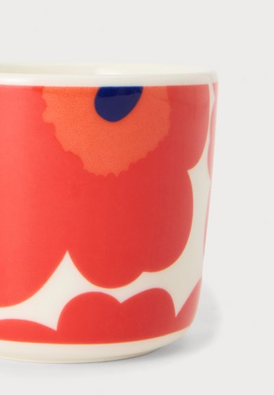 Керамична чаша с ярък червен и оранжев флорален мотив, с тъмносиня точка в центъра на цветето на бял фон.