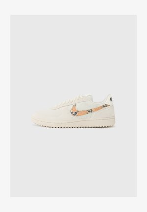 Fehér sneakers, textúrált velúr felsőrésszel, oldalukon színes kígyómintás Nike logóval és bézs gumitalppal.
