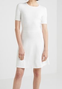 Robe blanche à manches courtes, en tissu tricoté texturé, corsage ajusté avec des rayures horizontales, jupe évasée et décolleté rond.