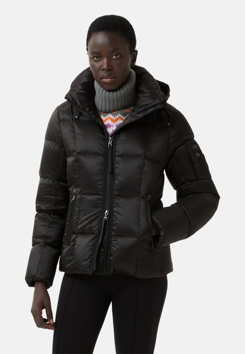 Černá péřová bunda s kapucí, prošívaný design, přední zip a boční kapsy. Pod tím je silný pletený šedý rolák.