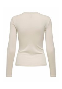 Langermet kremfarget topp laget av mykt, elastisk stoff med bølget halslinje og sømløst bakstykke, med en tettsittende silhuett.