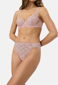 Spid lingerie sæt i blød pink. Bh'en har scallopkanter og blomstermønstre, med matchende spid thong, der fremhæver lignende detaljer.