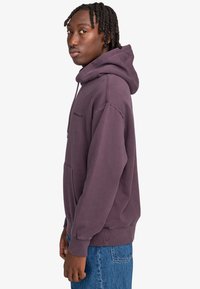 Felpa con cappuccio in un morbido misto cotone di colore viola tenue, dotata di tasca frontale e logo nero sul petto. Vestibilità casual con polsini a coste.